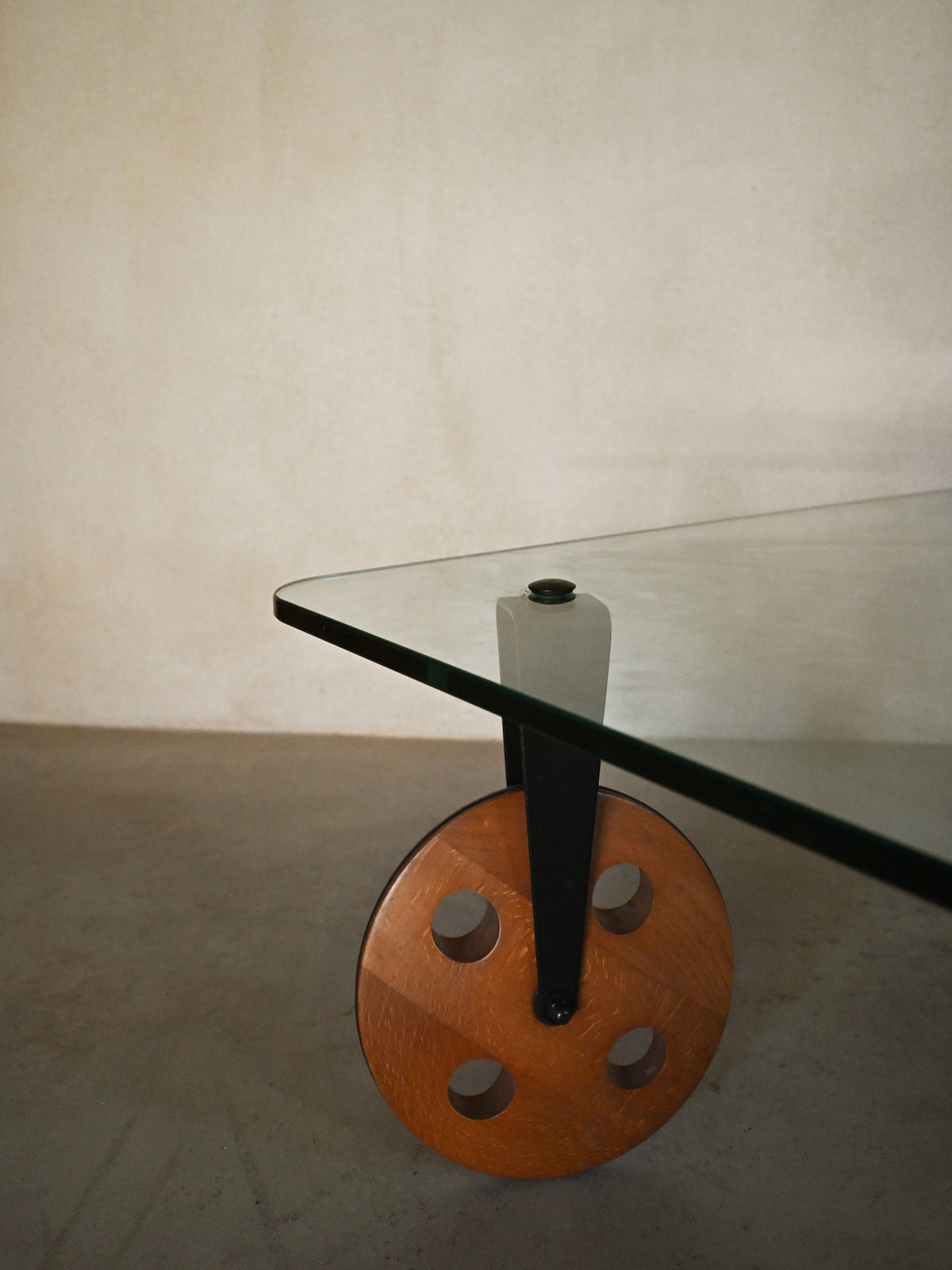 Gae Aulenti glass coffee table for FontanaArte, detail of a wooden castor wheel and black leg
