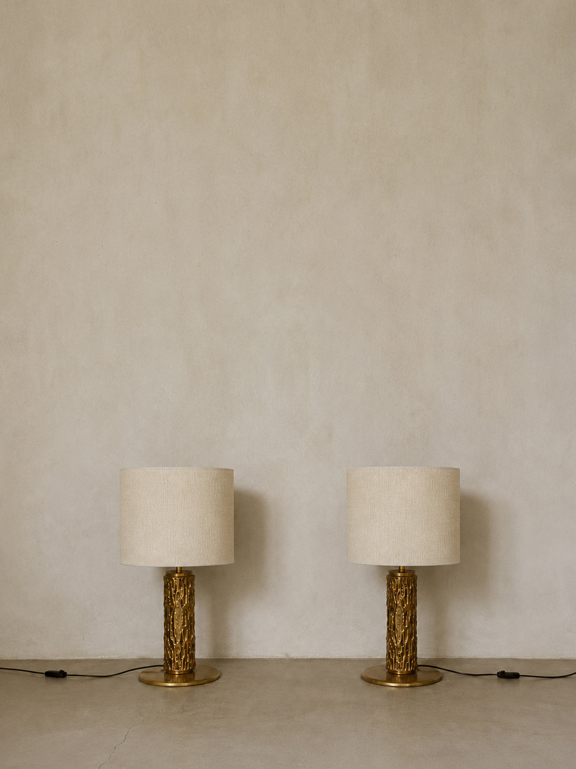 Luciano Frigerio cast metal table lamps, pair, the pair unlit against a plaster wall