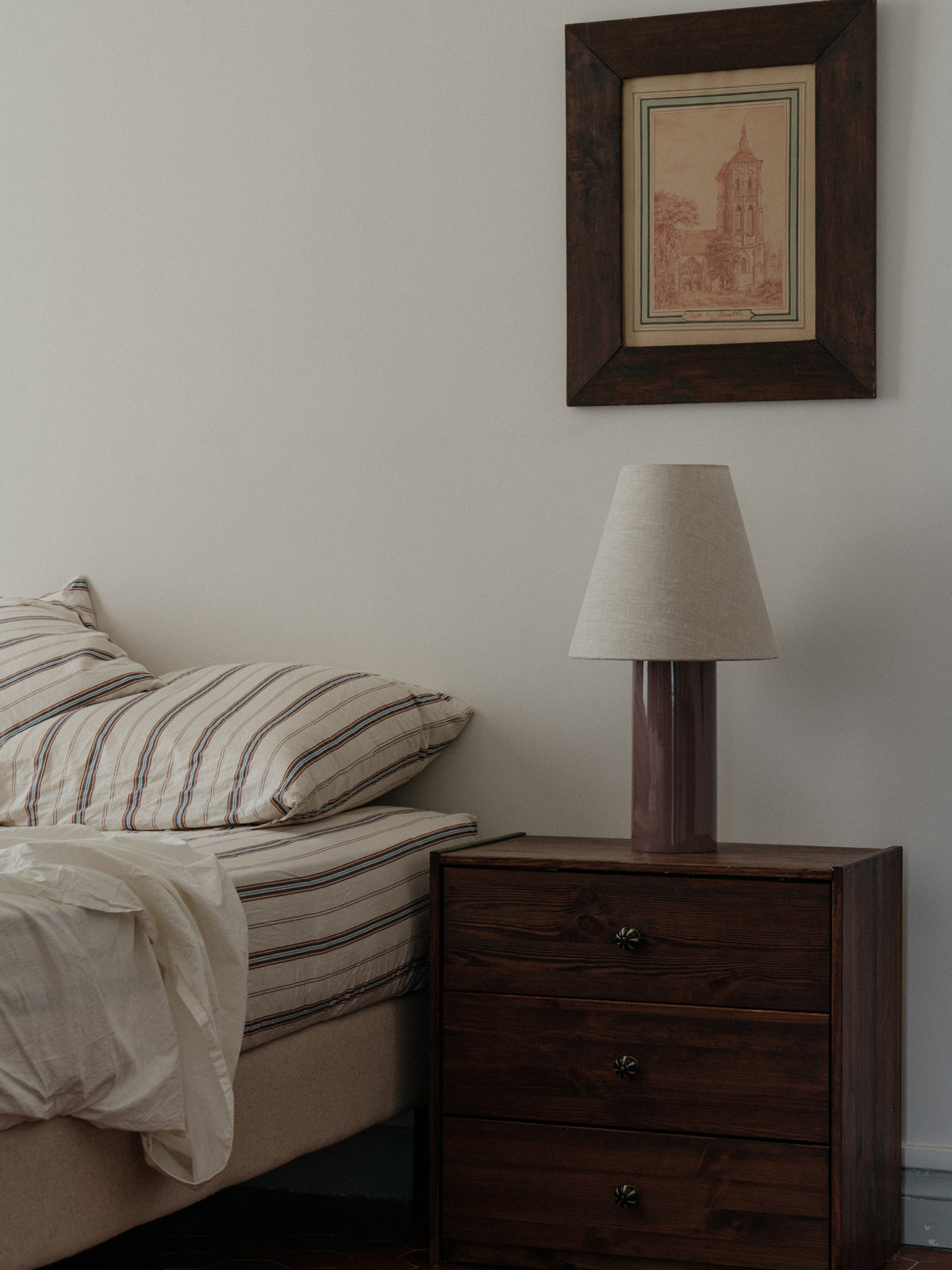 Giro Table Lamp in Bois de Rose, on a bedside chest, unlit