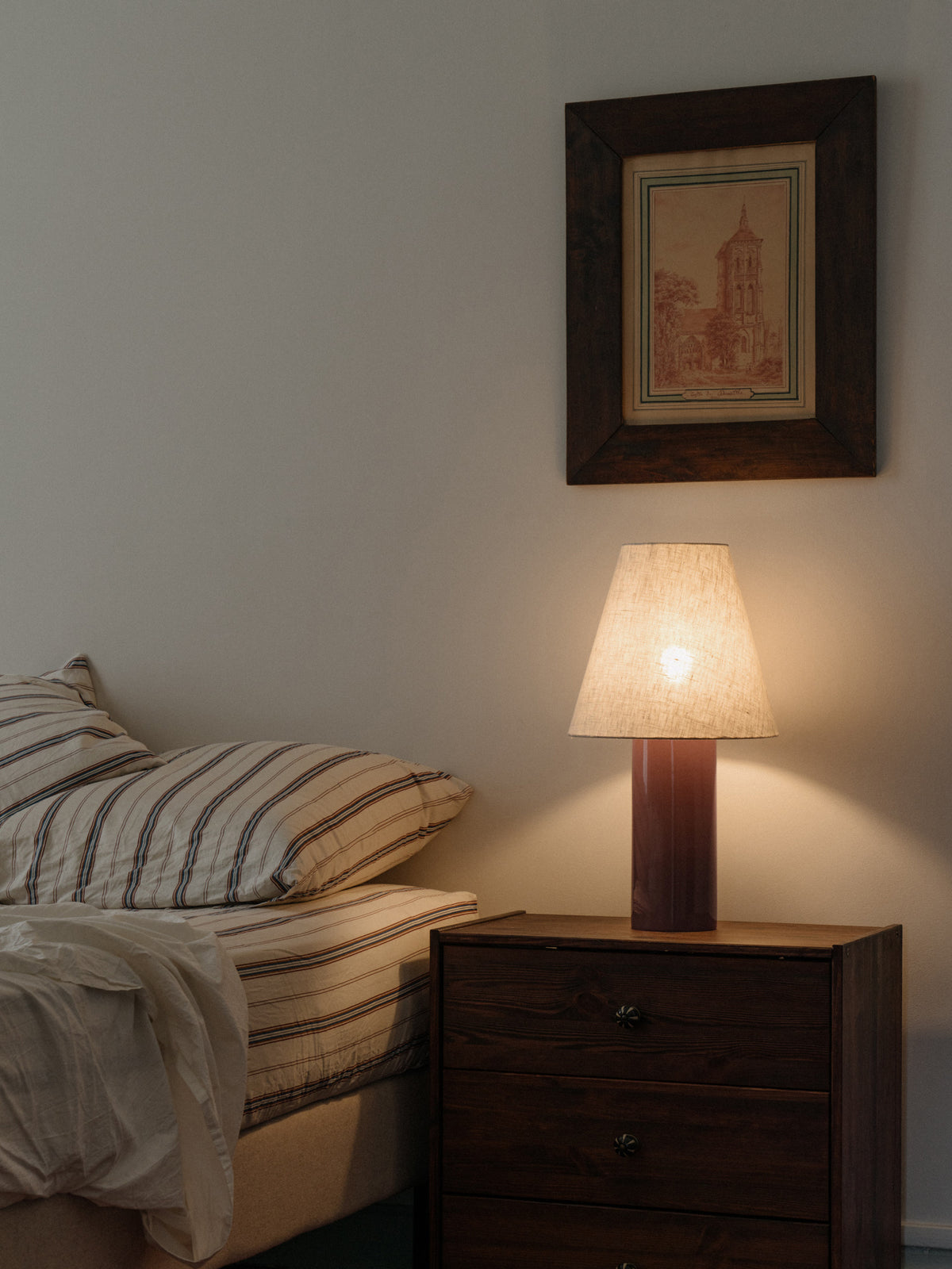 Giro Table Lamp in Bois de Rose, on a bedside chest, lit