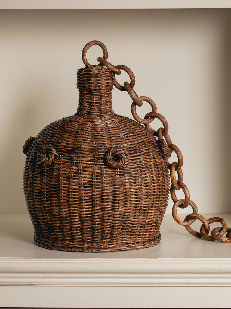 Heather Rattan Pendant Shade, Small, resting on a shelf beside its rattan chain