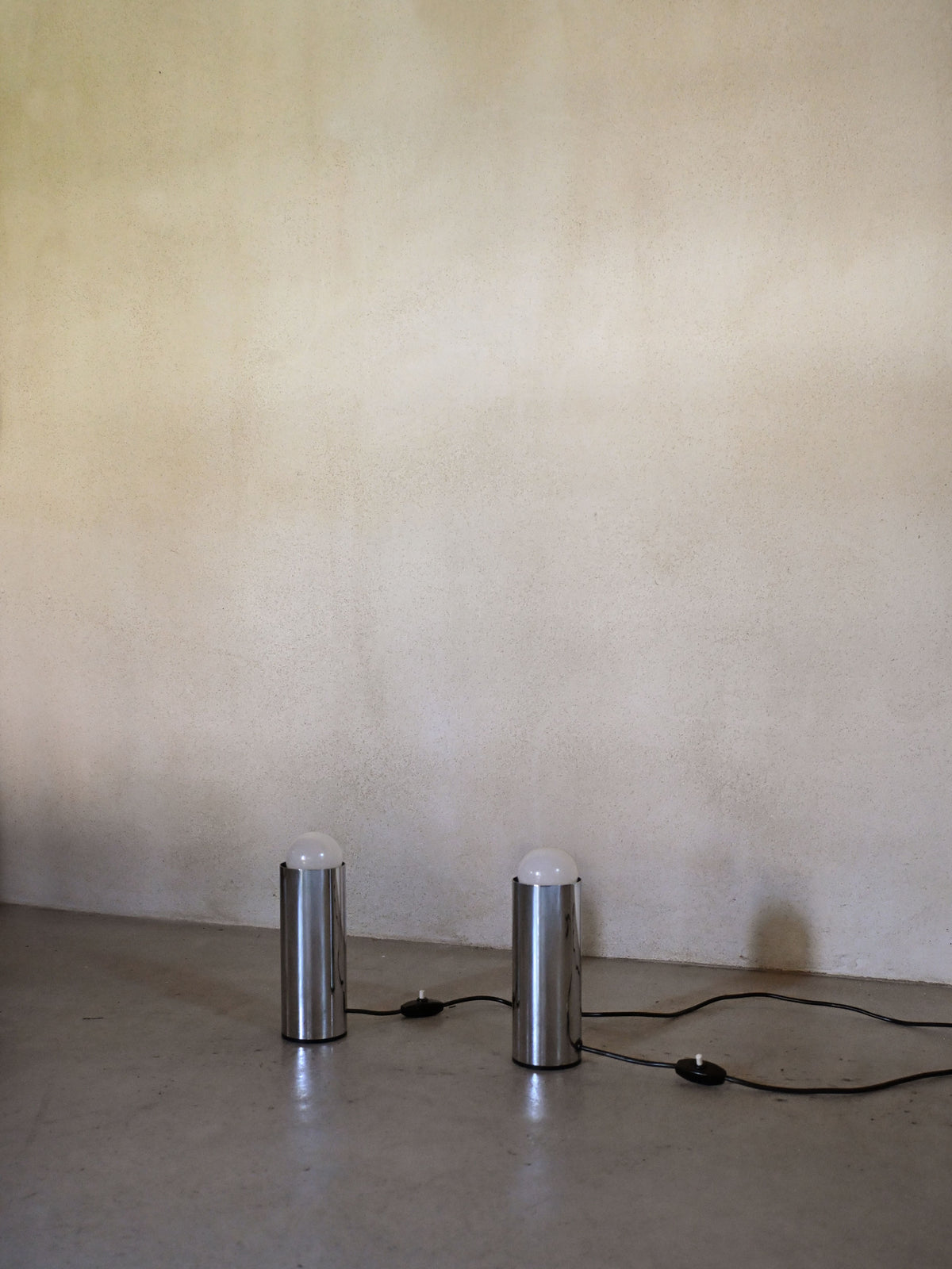 Enrico Tronconi chrome table lamps, pair, the pair unlit, chrome cylinders against a plaster wall