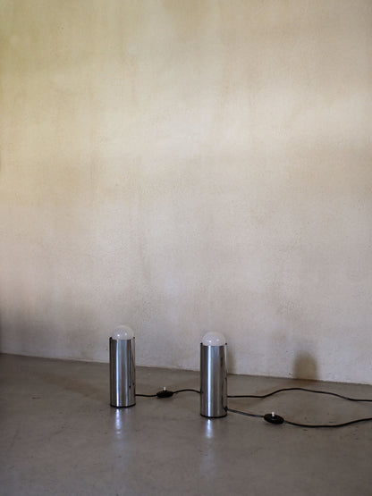Enrico Tronconi chrome table lamps, pair, the pair unlit, chrome cylinders against a plaster wall