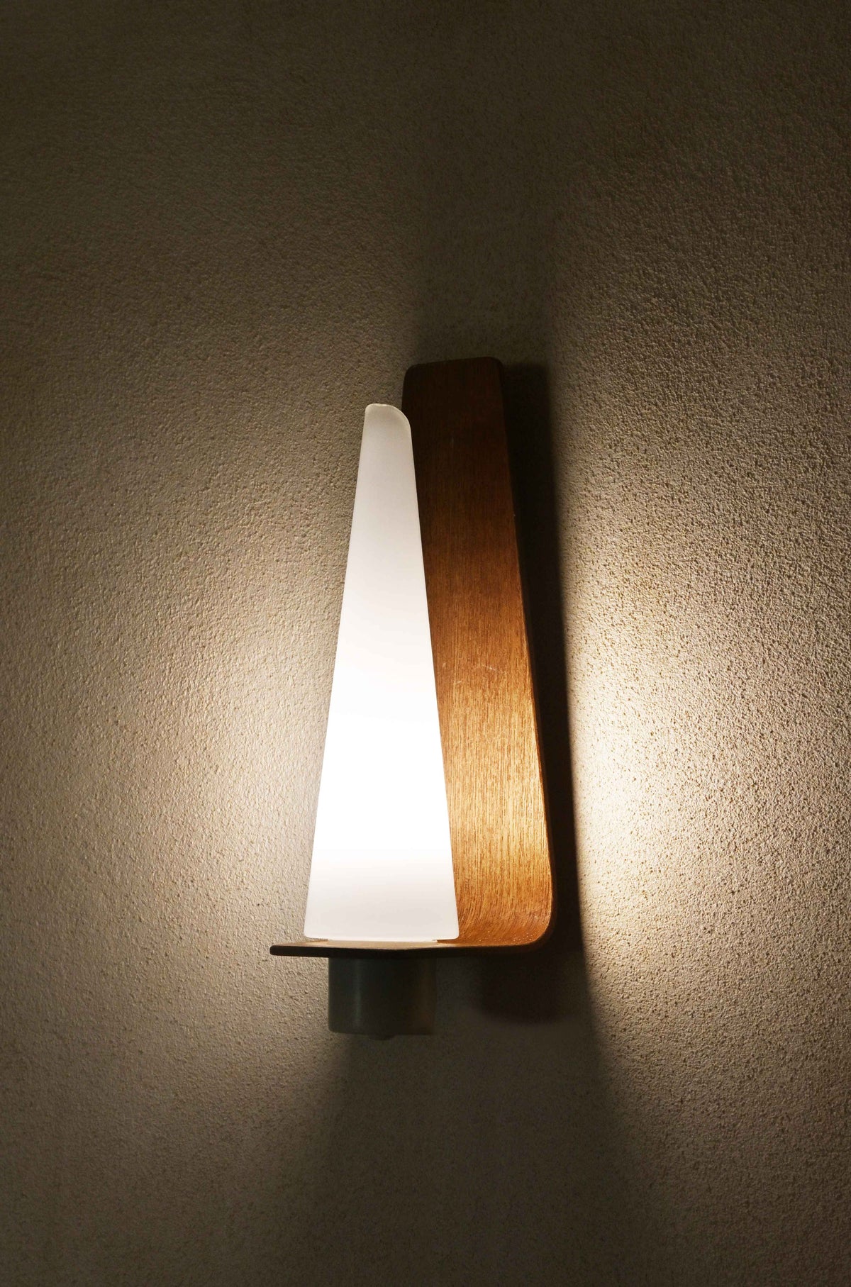 "Pinetti" wood and frosted glass sconce, a single sconce lit, seen from the opposite side
