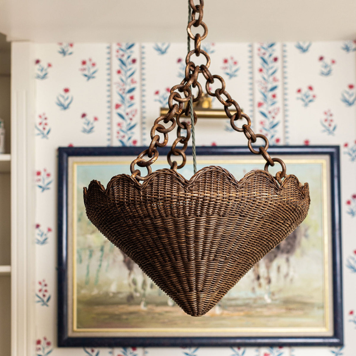 Primrose Rattan Pendant Shade, hanging in front of a framed painting