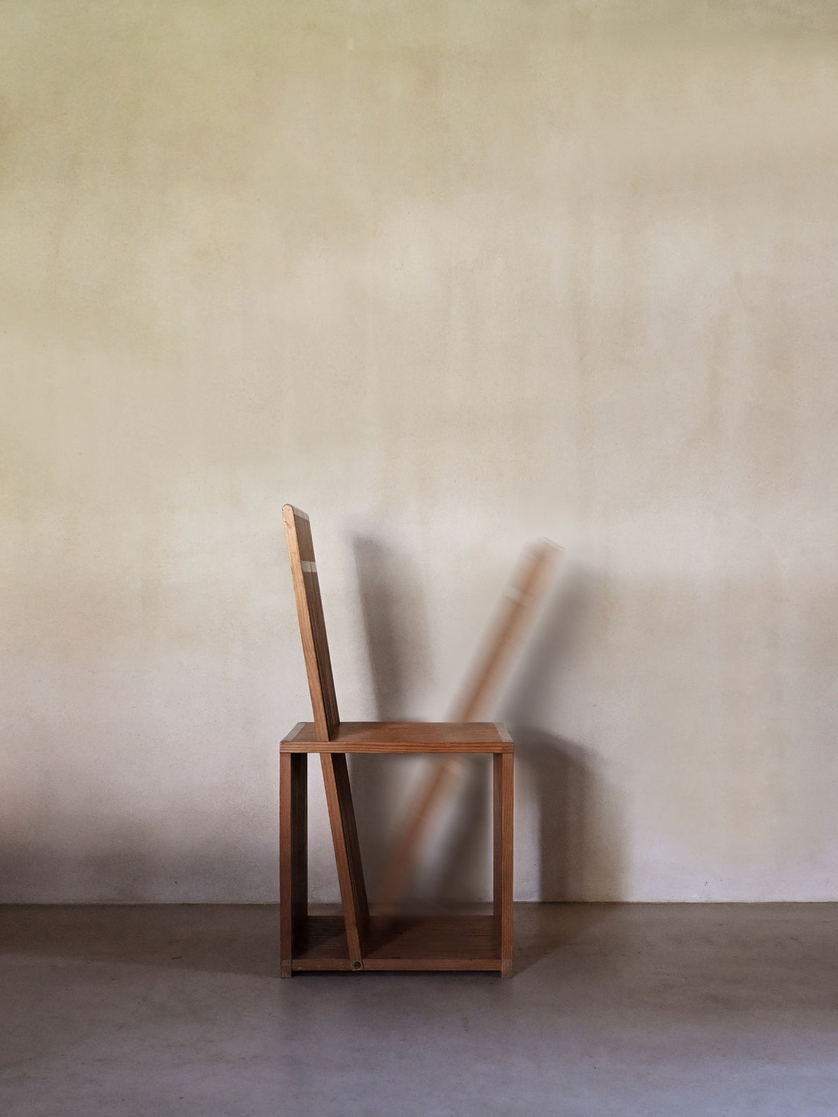 Brutalist wood Strips occasional chair, rear view against a plaster wall
