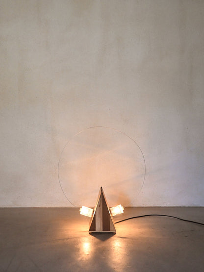 Studio A.R.D.I.T.I. "BT1972" lamp, lit, showing the glow cast across the wall behind