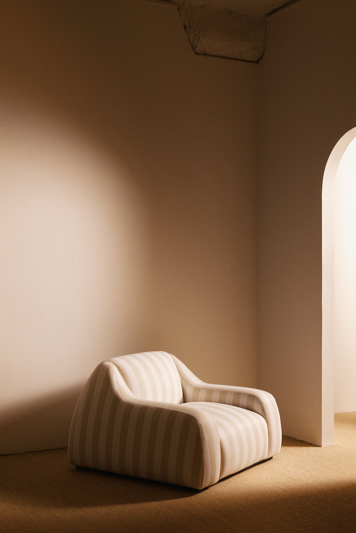 AS02 armchair in Jim Thomson Matelot Sea Shell fabric, angled view in the room by an arched doorway