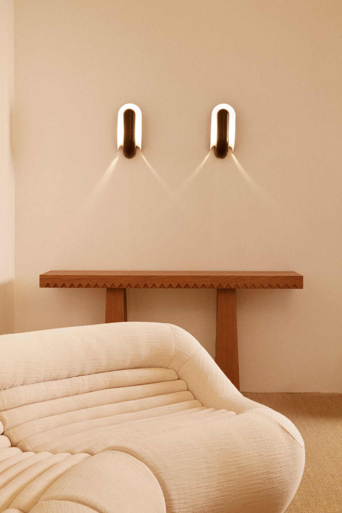 Baga oak console table, view above a curved sofa with two wall lights