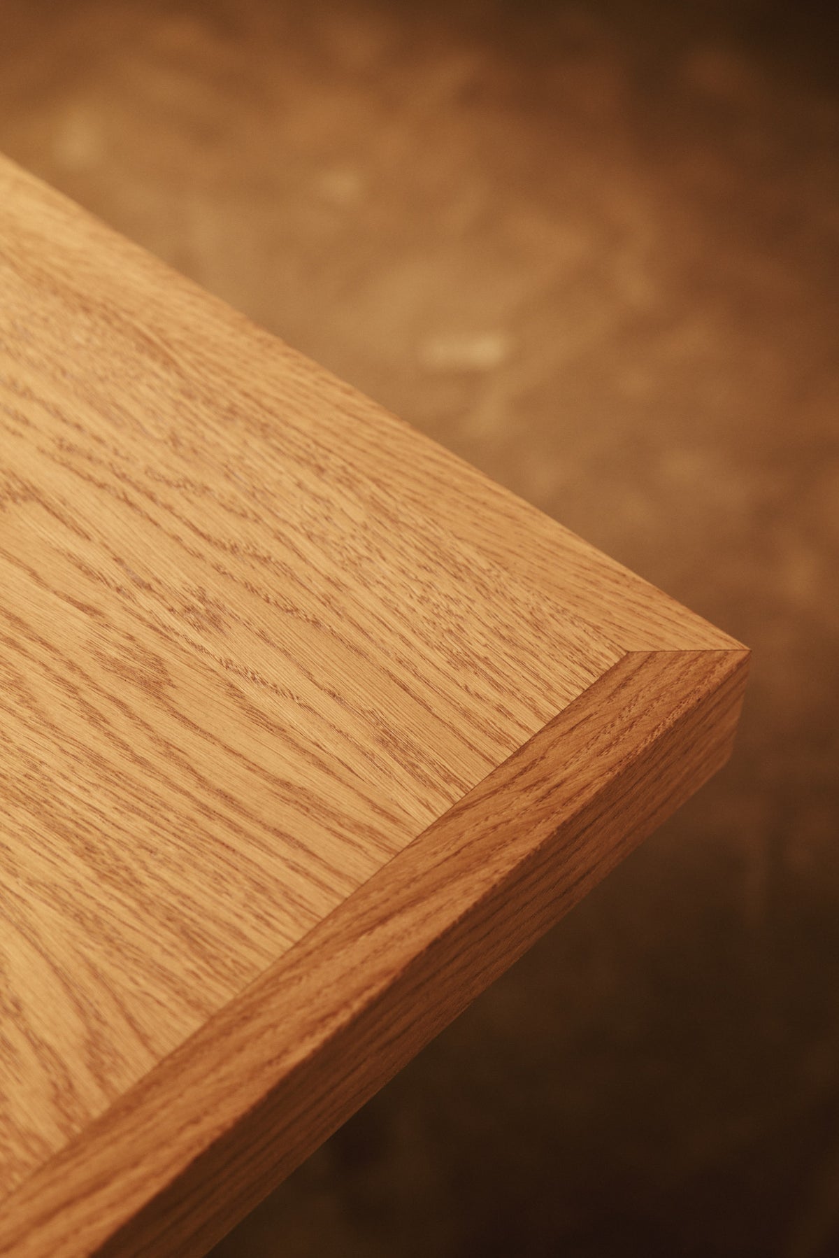 Moon dining table in solid oiled oak, close view of the corner of the oak top