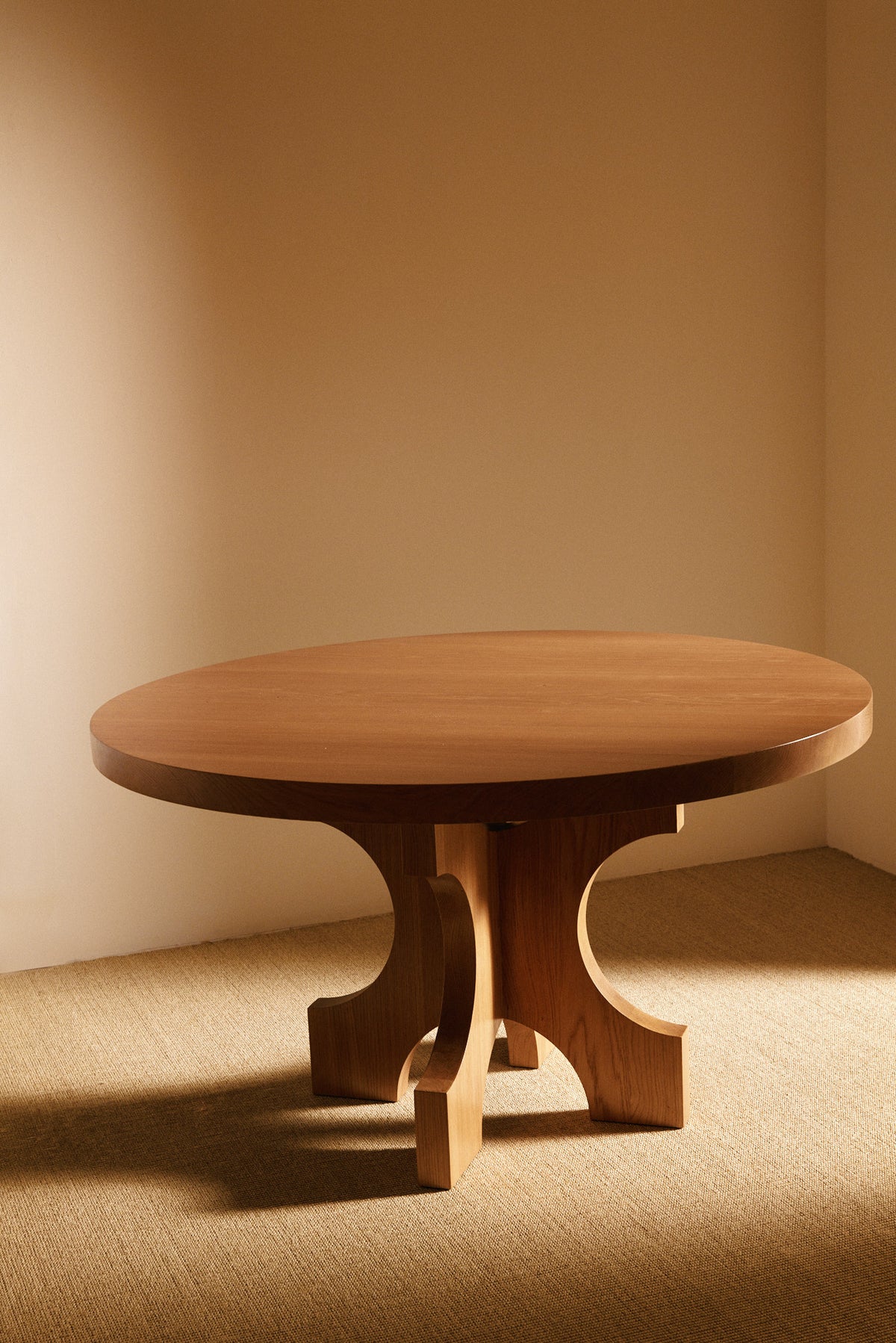 Orion round dining table in solid oiled oak, angled view of the round top and base