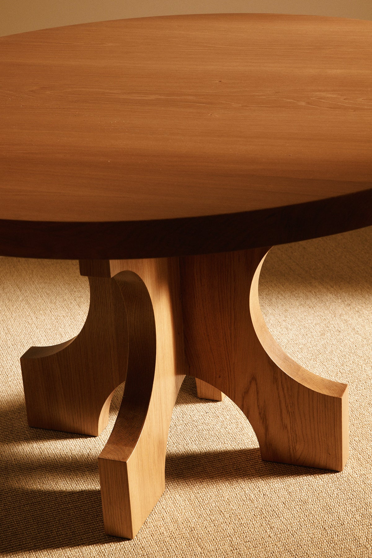 Orion round dining table in solid oiled oak, angled view of the four footed base