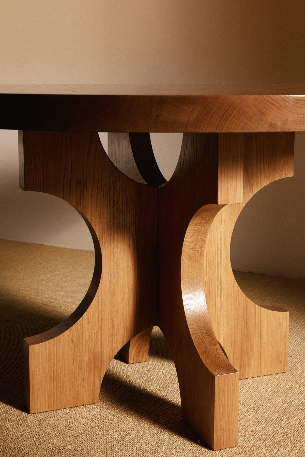 Orion round dining table in solid oiled oak, closer view of the curved base under the top