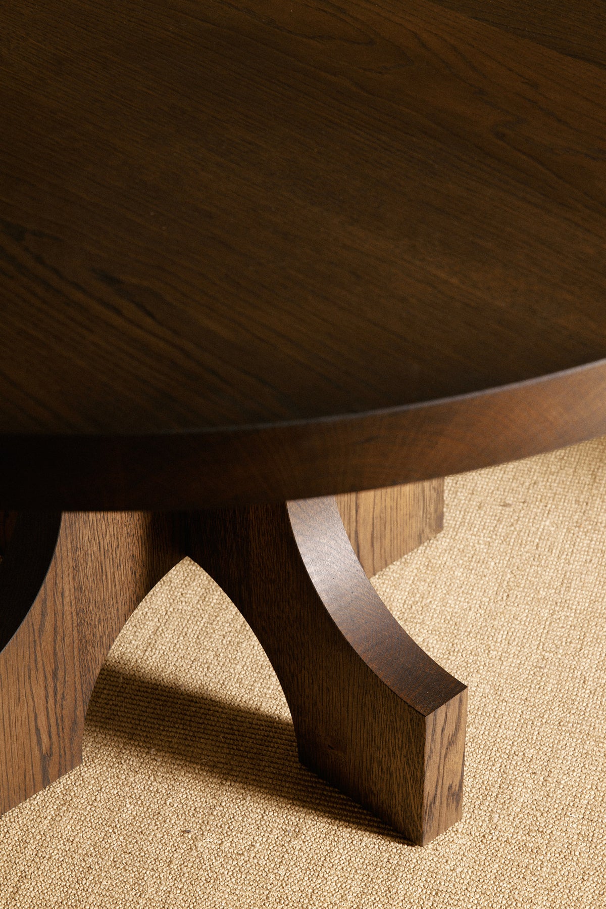 Orion round dining table in solid oiled oak, nearer view of the base and top edge in a darker tone