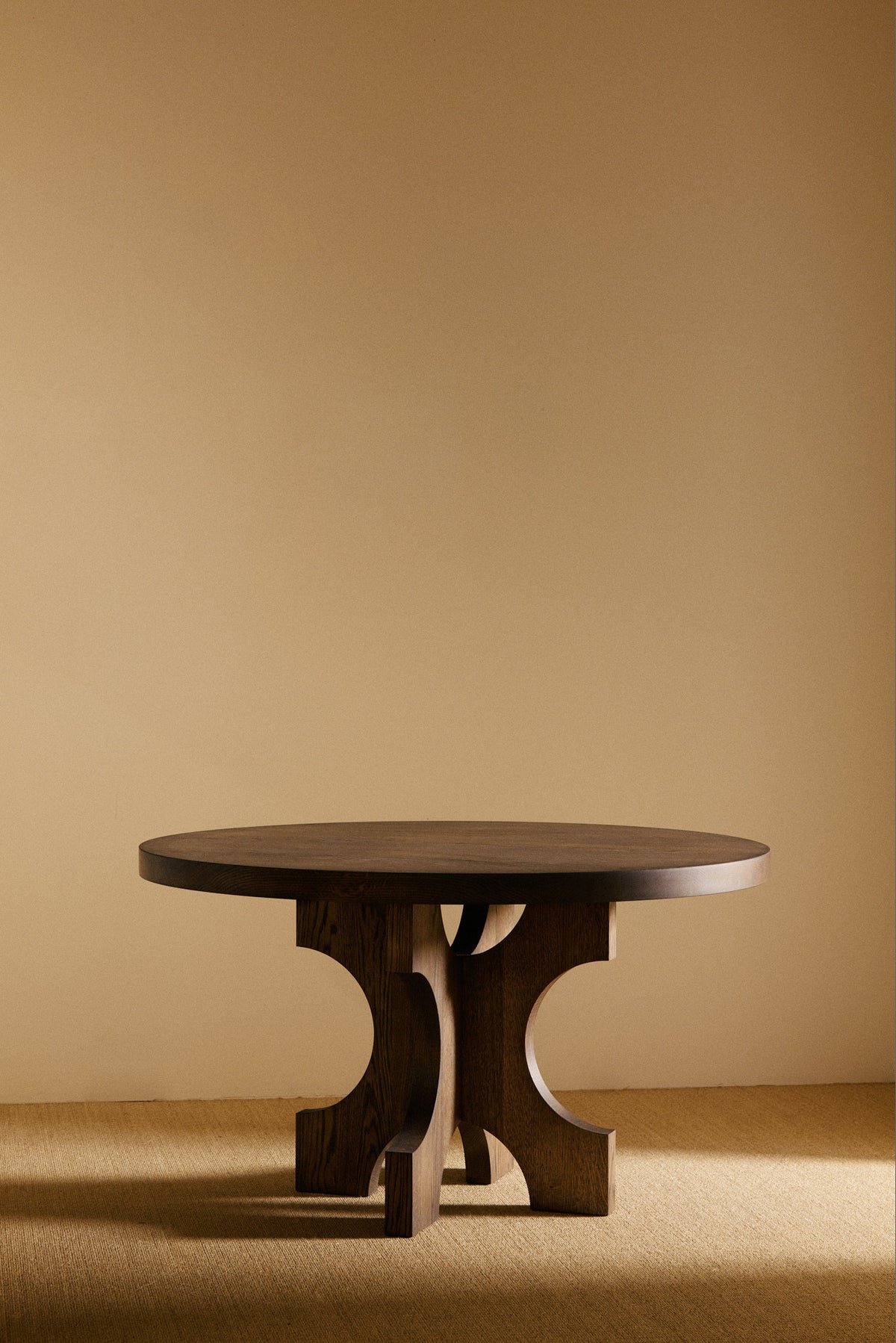 Orion round dining table in solid oiled oak, front view of the table in a darker tone
