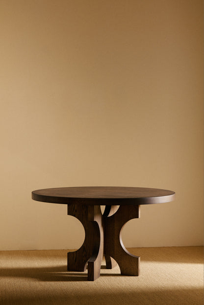 Orion round dining table in solid oiled oak, front view of the table in a darker tone