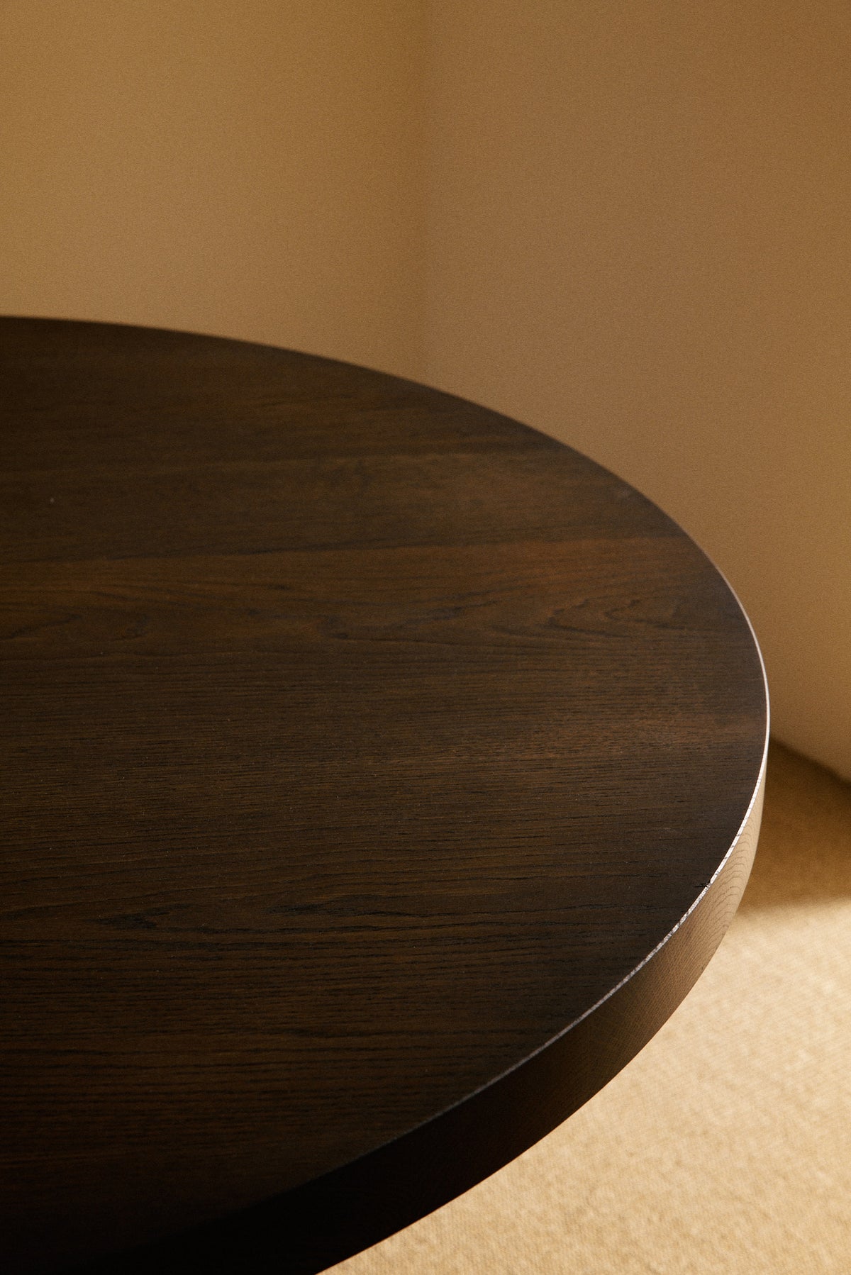 Orion round dining table in solid oiled oak, close view of the round top edge in a darker tone