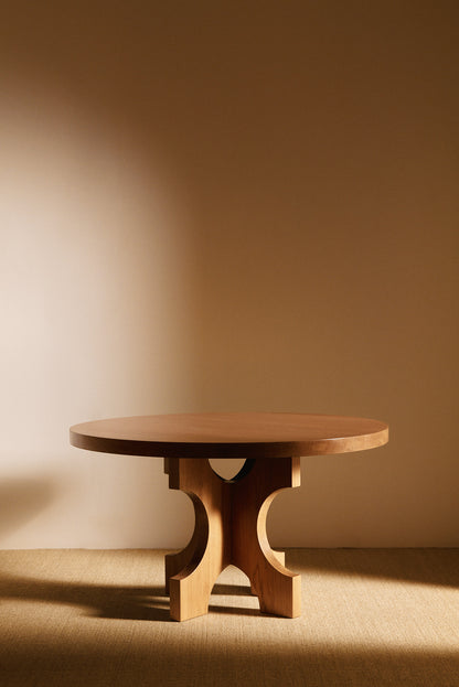 Orion round dining table in solid oiled oak, front view with the arched base