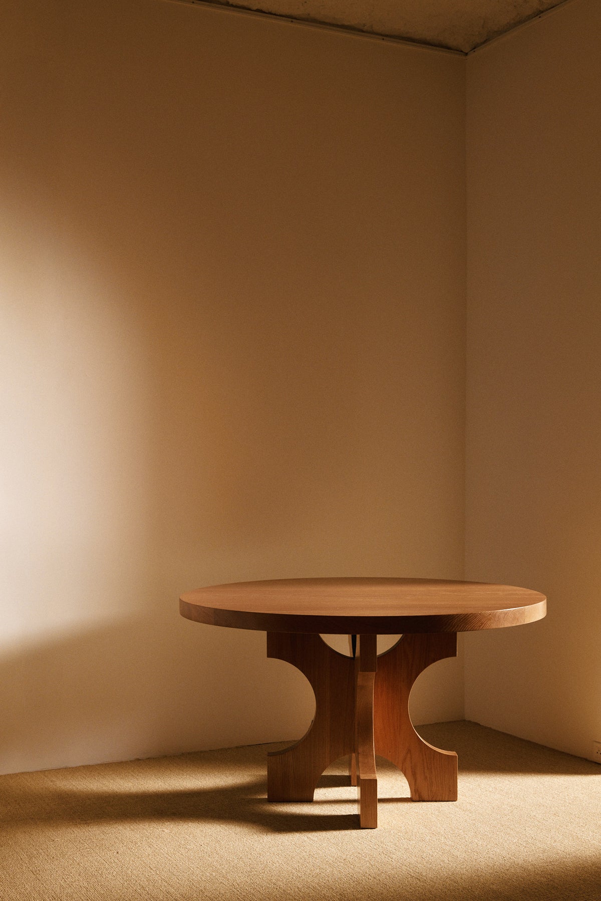 Orion round dining table in solid oiled oak, front view of the round table in the room