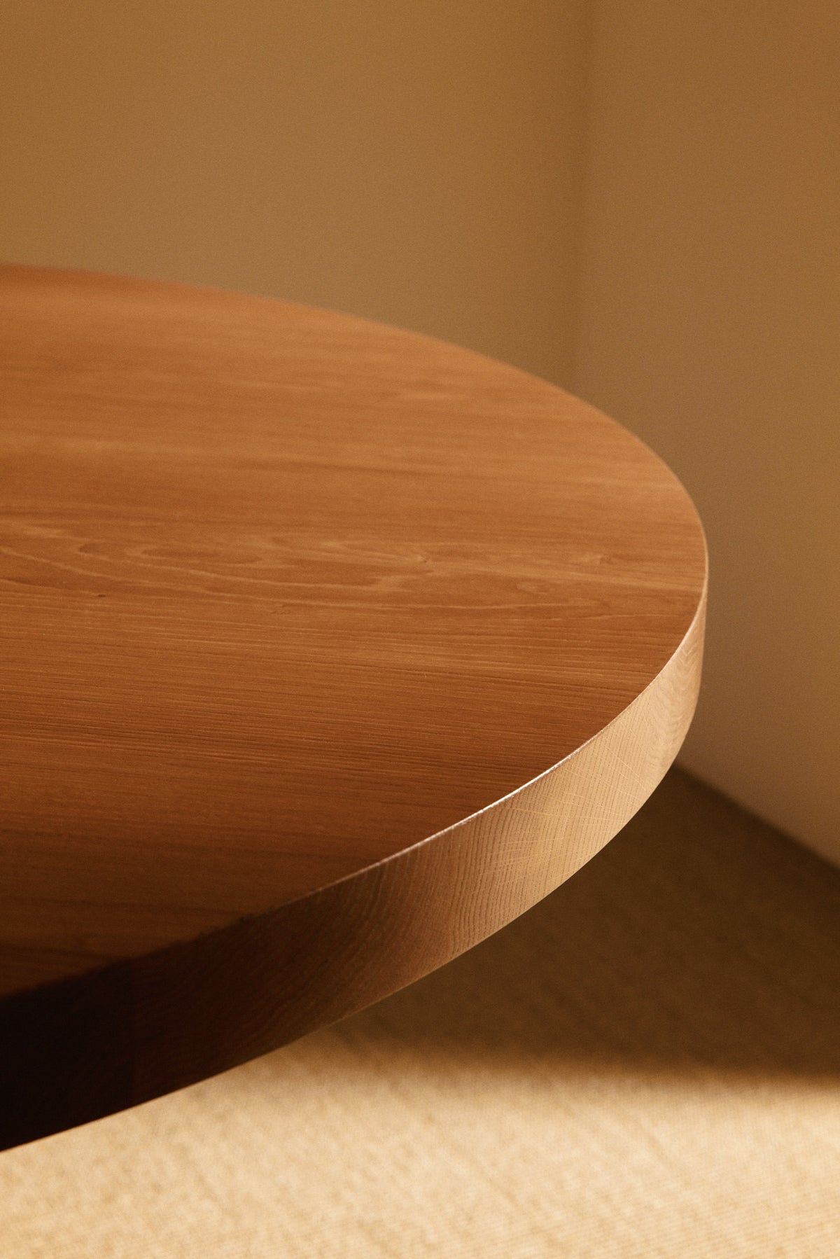 Orion round dining table in solid oiled oak, close view of the round oak top and its edge