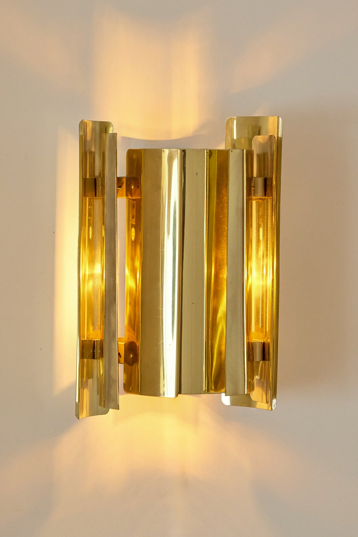 Falkenbergs Belysning brass sconce, front view of the folded brass sheets, lit
