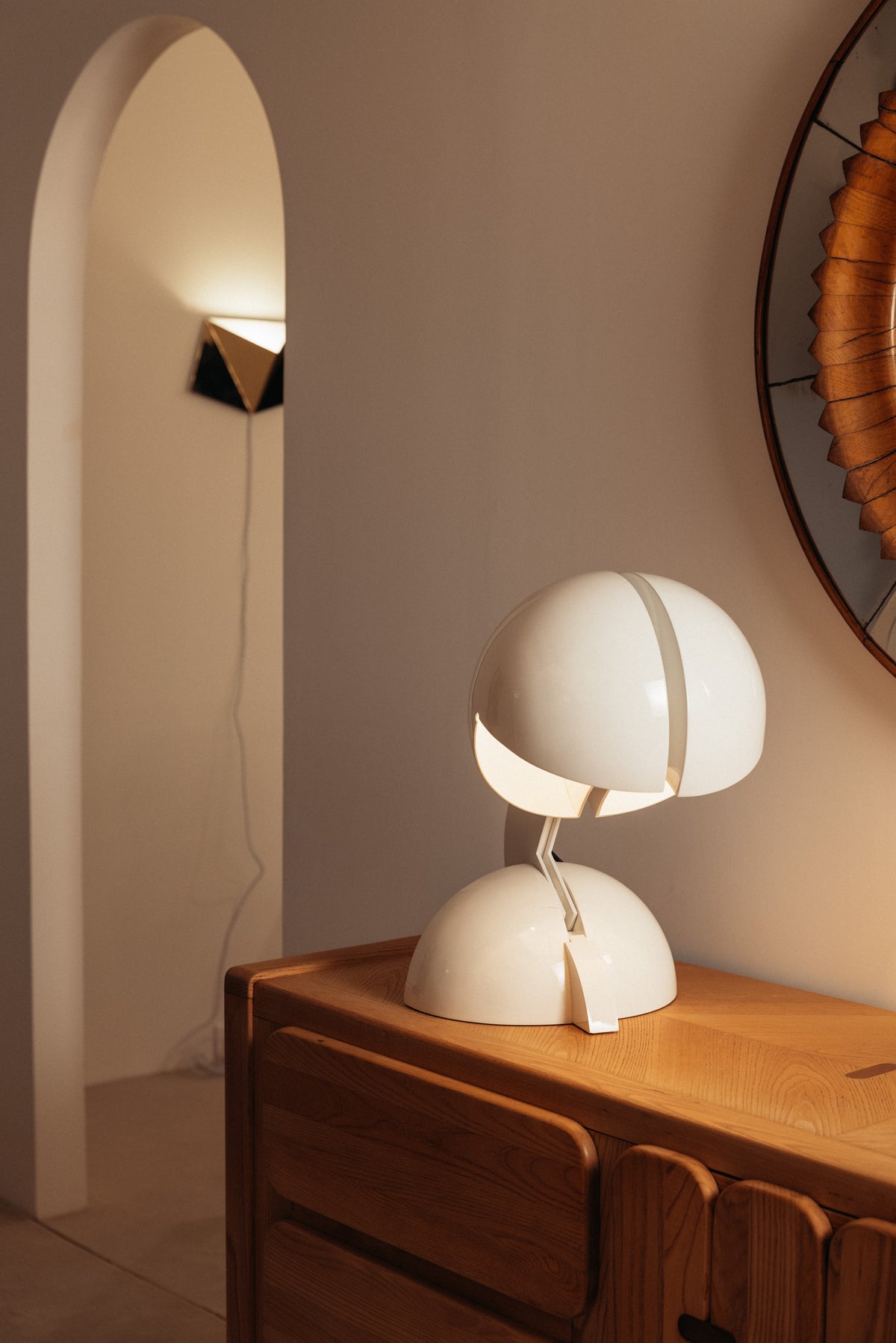 Gae Aulenti enameled aluminum Ruspa table lamp, hood open toward the light beside an arched niche