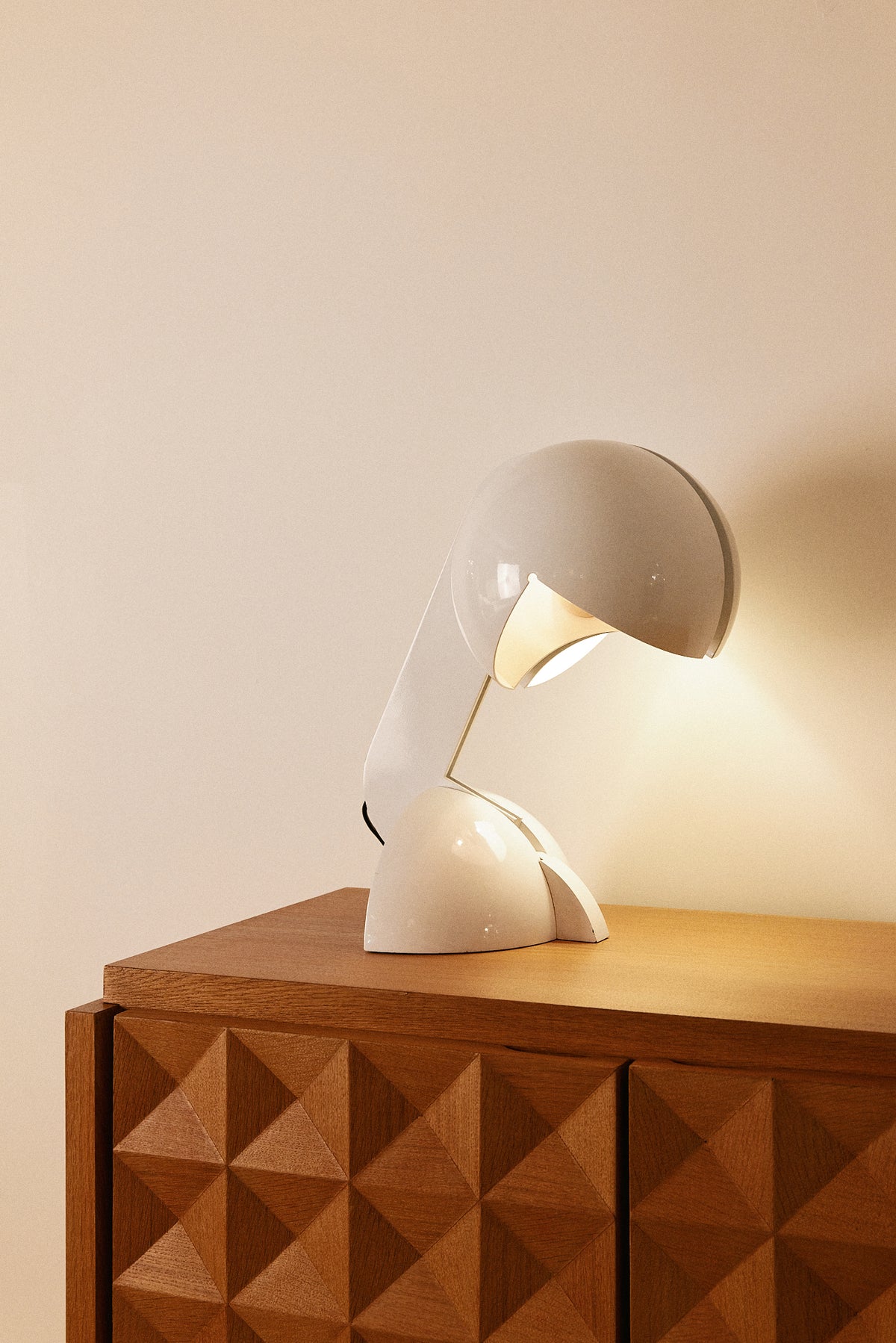 Gae Aulenti enameled aluminum Ruspa table lamp, lit on a console with a faceted cabinet