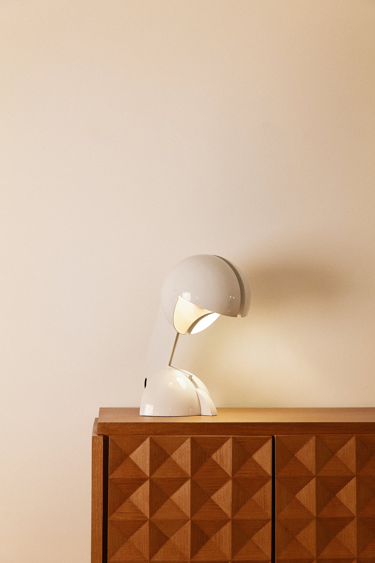 Gae Aulenti enameled aluminum Ruspa table lamp, wide view lit on a console against a plain wall