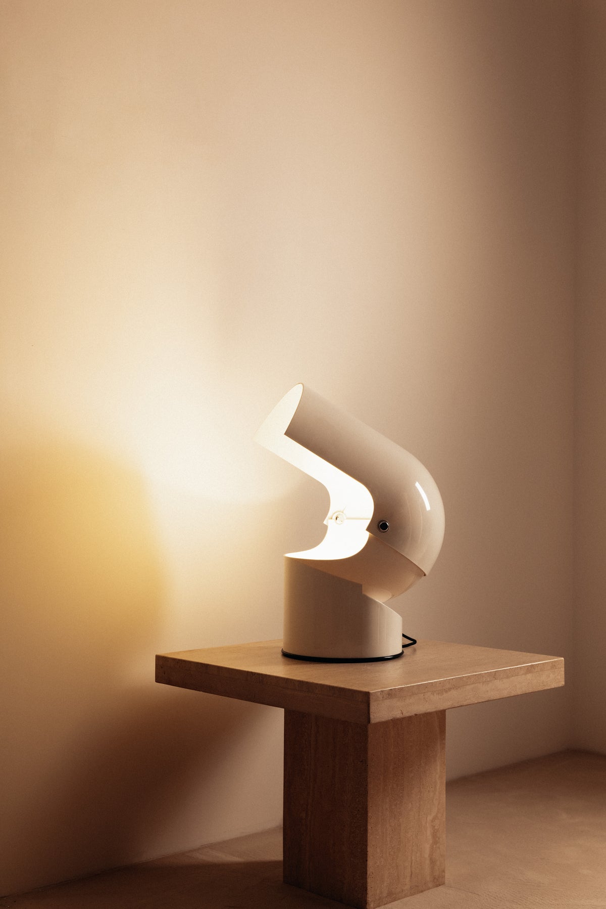 Gae Aulenti molded ABS Mezzo Pileo table lamp, wide view on a square table with the hood tilted
