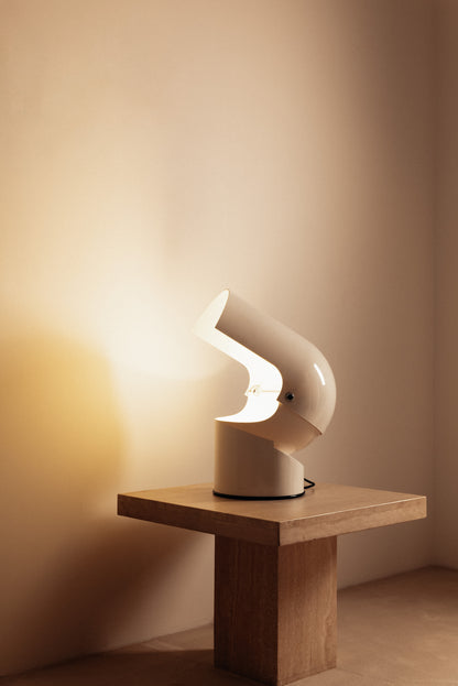 Gae Aulenti molded ABS Mezzo Pileo table lamp, wide view on a square table with the hood tilted