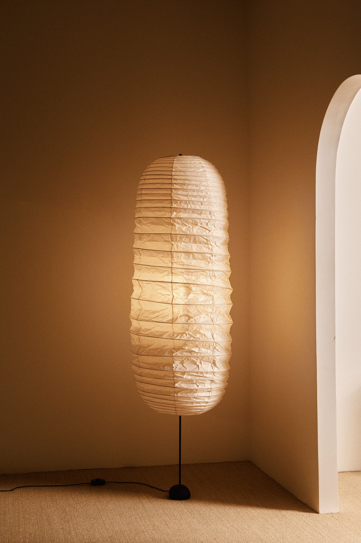 Isamu Noguchi Akari 32N floor lamp, full view beside an arched wall
