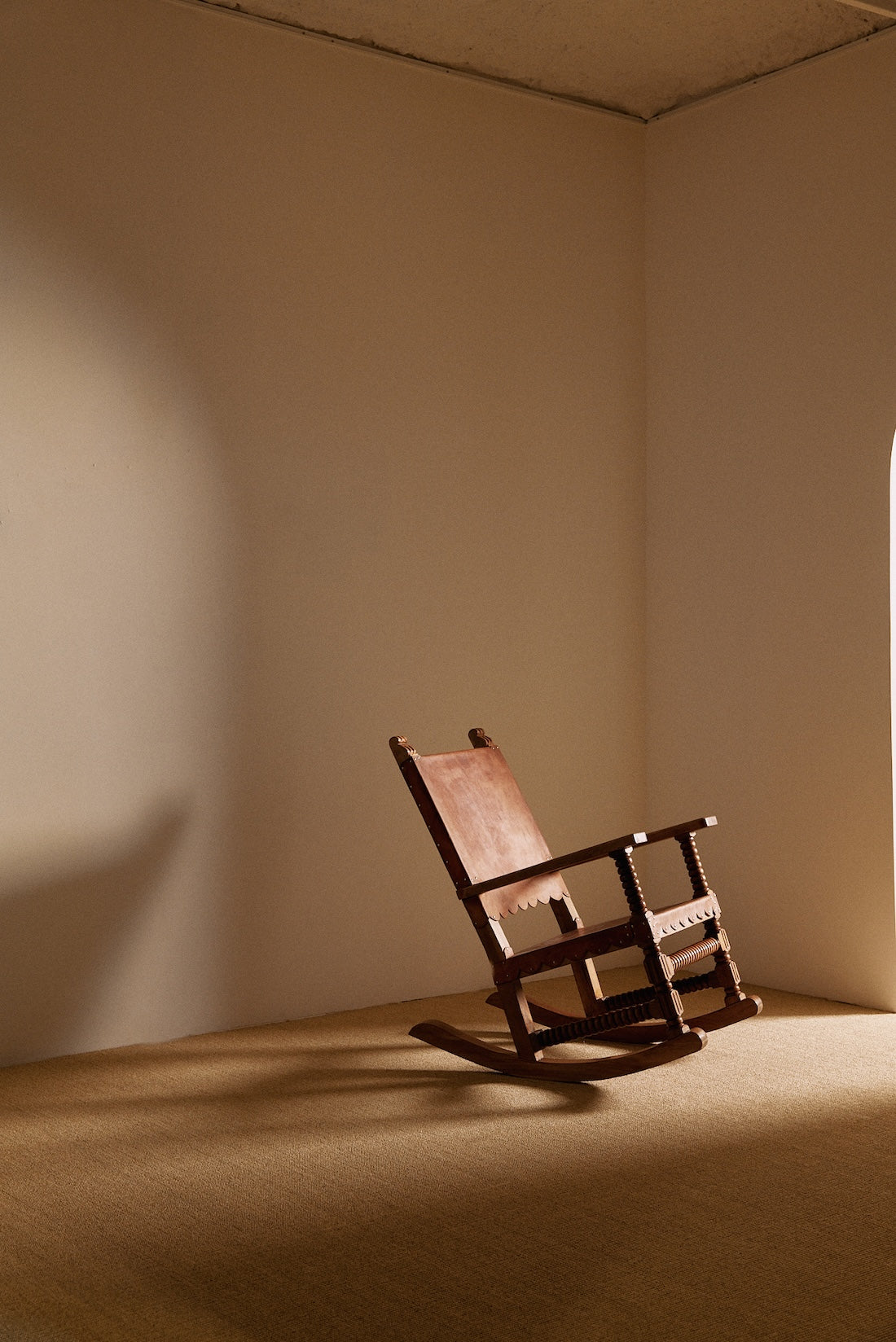 Mexican oak and tanned leather rocking chair, angled view in the corner