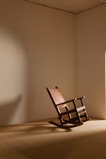 Mexican oak and tanned leather rocking chair, angled view in the corner