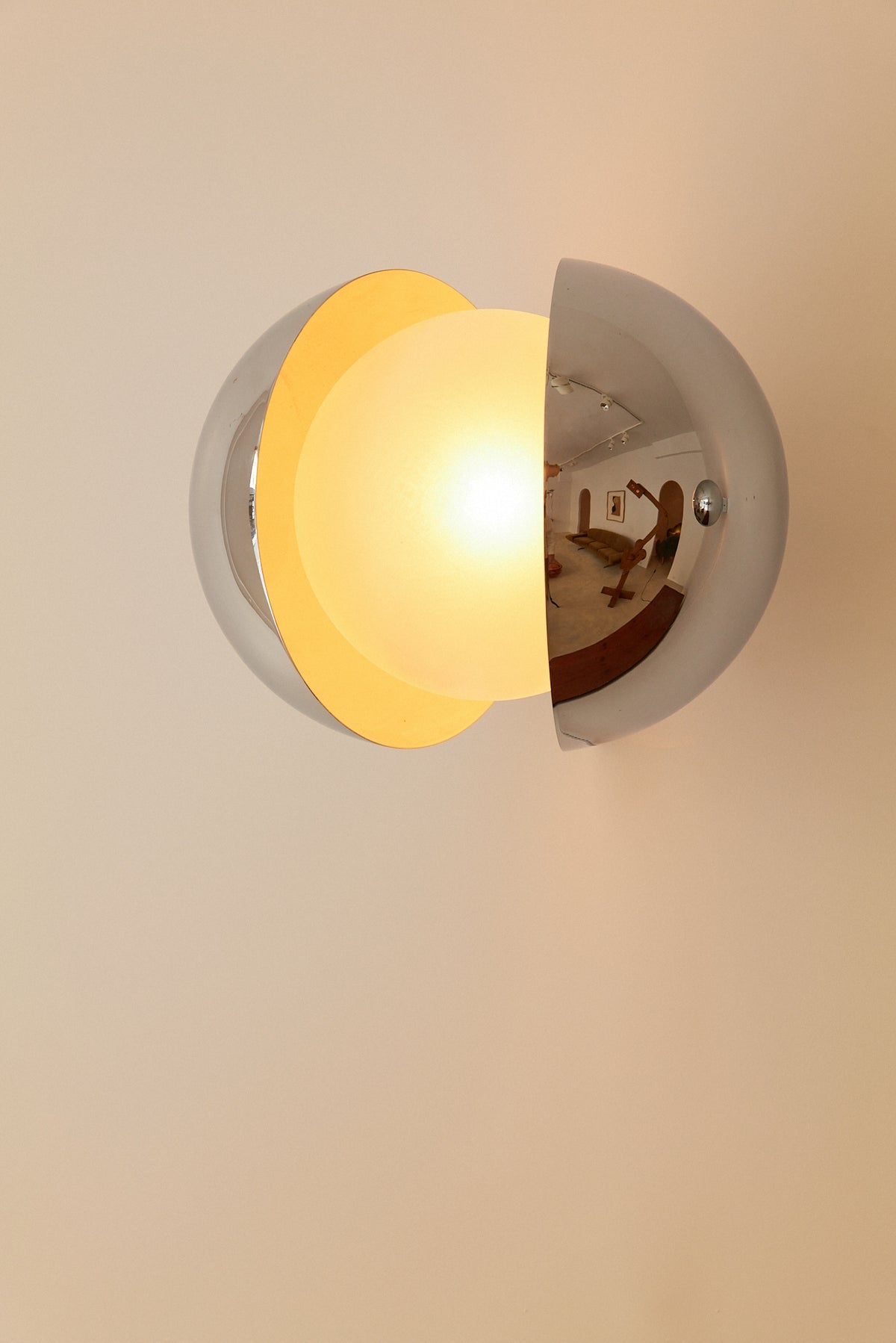 Gian Emilio, Piero & Anna Monti Diaframma polished steel and glass wall sconce, front view with the glass globe lit inside the opening
