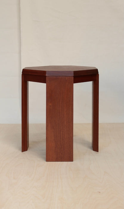 Paris Side Table in sapele mahogany, three quarter view of the octagonal top and flat slab legs on a pale birch floor