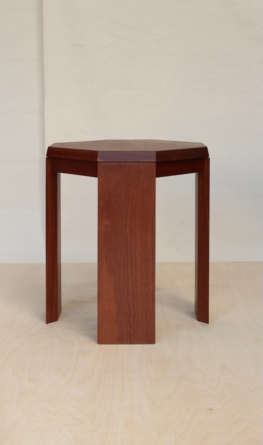 Paris Side Table in sapele mahogany, three quarter view of the octagonal top and flat slab legs on a pale birch floor