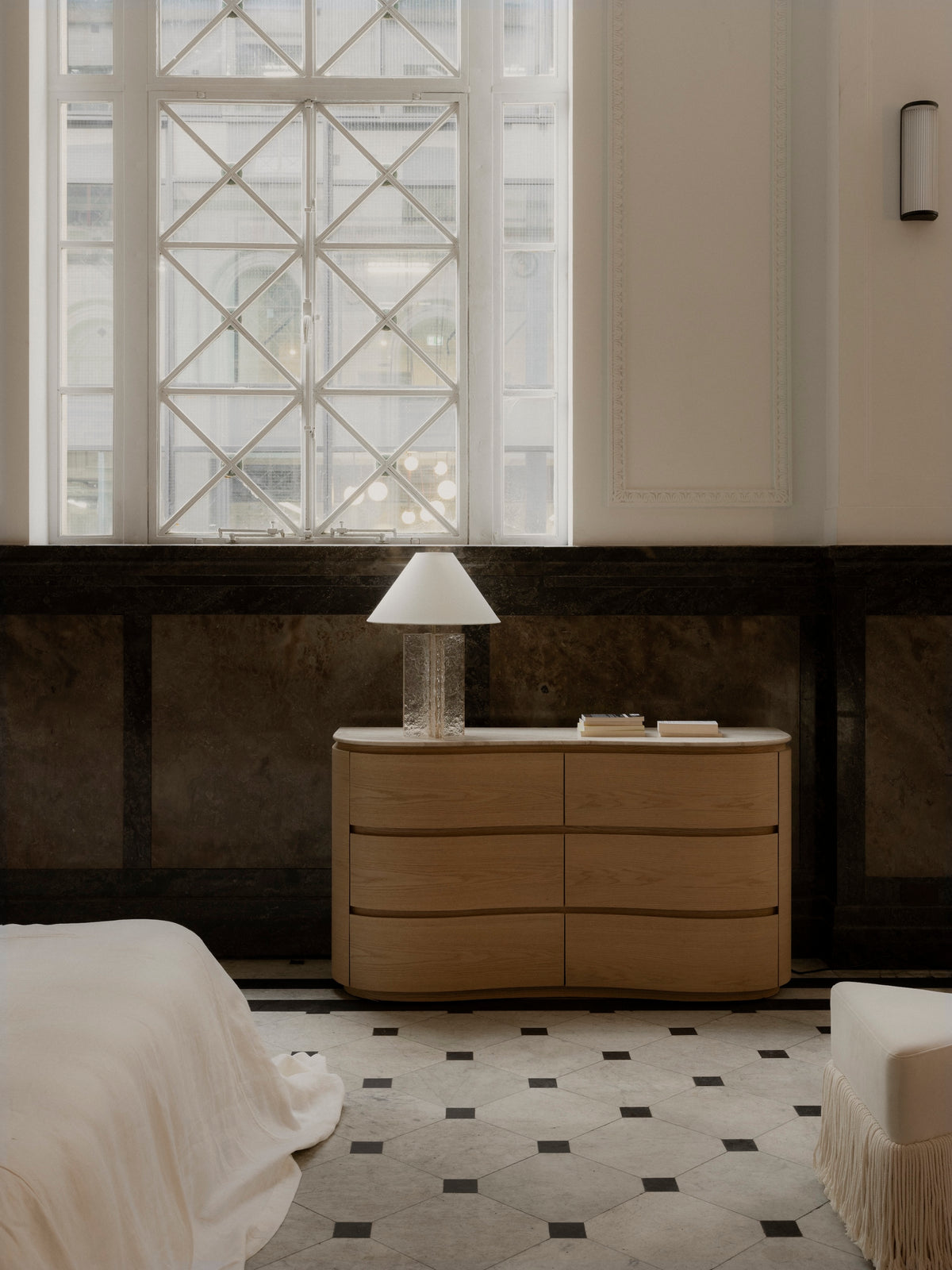 Remy Dresser in Palomino with a glass lamp beneath a casement window, Allard Ottoman in Milk at right